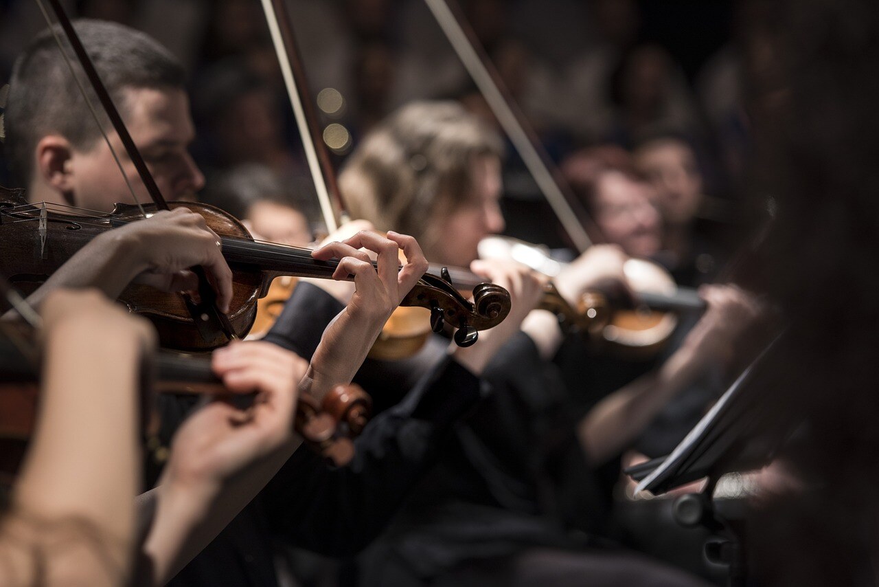 Close up of people playing violins in orchestra